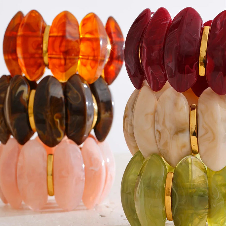 "Adalaide Bangle — chunky marbled resin beads in a sculptural wave design, finished with polished gold spacer links. A bold pop of color for stacking or wearing solo. Available in six rich marbled tones."