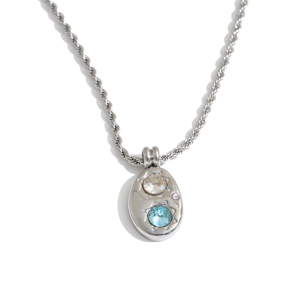 Shop the Alba Necklace: celestial-inspired oval pendant with aqua blue zircon. Waterproof stainless steel, silver or 18k gold-tone.
