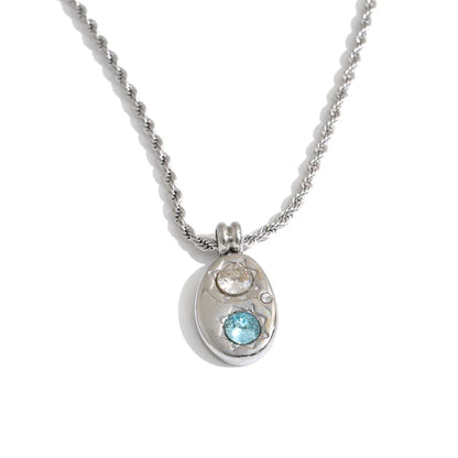 Shop the Alba Necklace: celestial-inspired oval pendant with aqua blue zircon. Waterproof stainless steel, silver or 18k gold-tone.