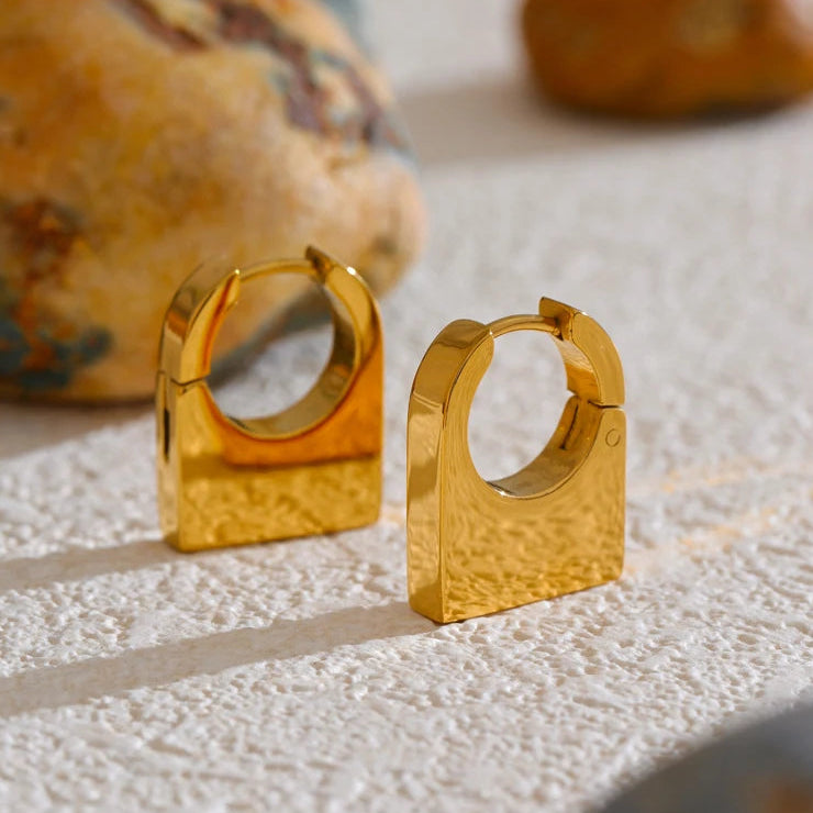 Gold hoop earrings on a textured surface with a blurred background