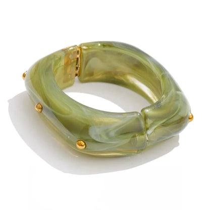 Green bangle with gold accents on a white background