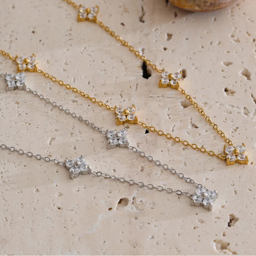 Two gold and silver necklaces with star-shaped pendants on a textured beige surface. Waterproof