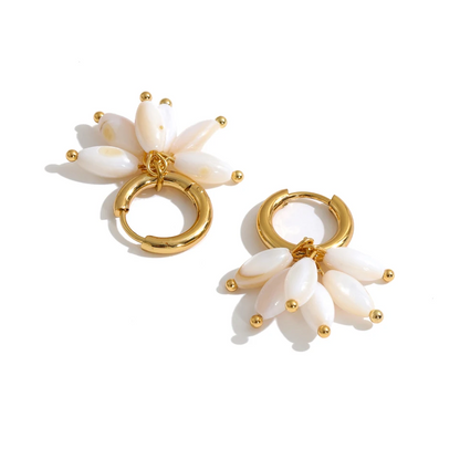 A pair of gold hoop earrings with dangling flower charms made of glossy white shell-like petals and small gold bead accents, shown on a clean white background.