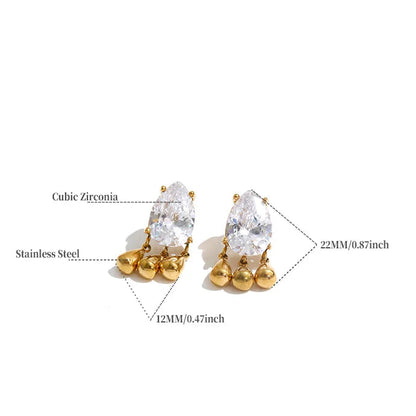 A product information graphic showing a pair of gold-toned stud earrings with large clear cubic zirconia stones and small round gold beads at the base, with measurement callouts and a small spec table below on a white background.
