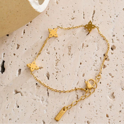 Gold bracelet with star-shaped charms on a textured beige surface