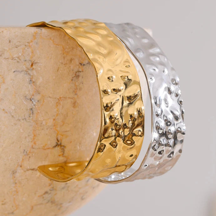 Gold and silver bangle on a stone surface with a neutral background