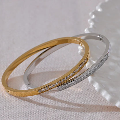 Two gold and silver bangles with diamond accents on a light fabric background