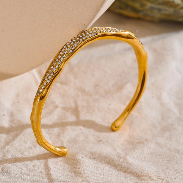 Gold bracelet with embedded stones on a textured surface
