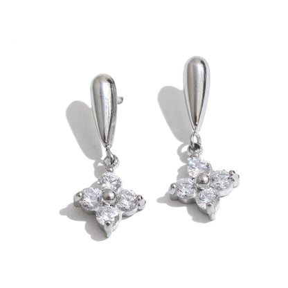 A pair of silver-toned drop earrings with teardrop-shaped hooks and four-prong flower charms set with clear stones, shown on a white background with soft shadows.