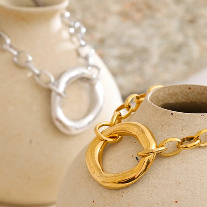 Gold and silver stainless steel bracelets on a ceramic surface with a blurred background