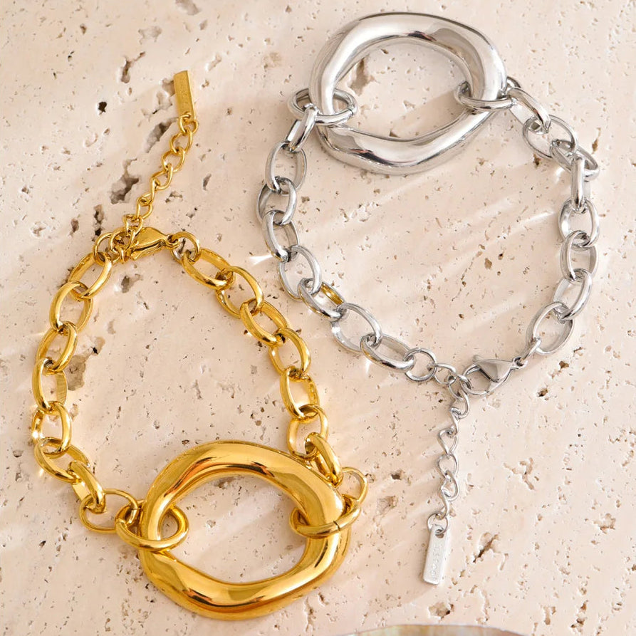 Gold and silver chain bracelets on a textured beige surface