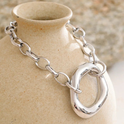 Silver chain bracelet on a ceramic vase with a natural background