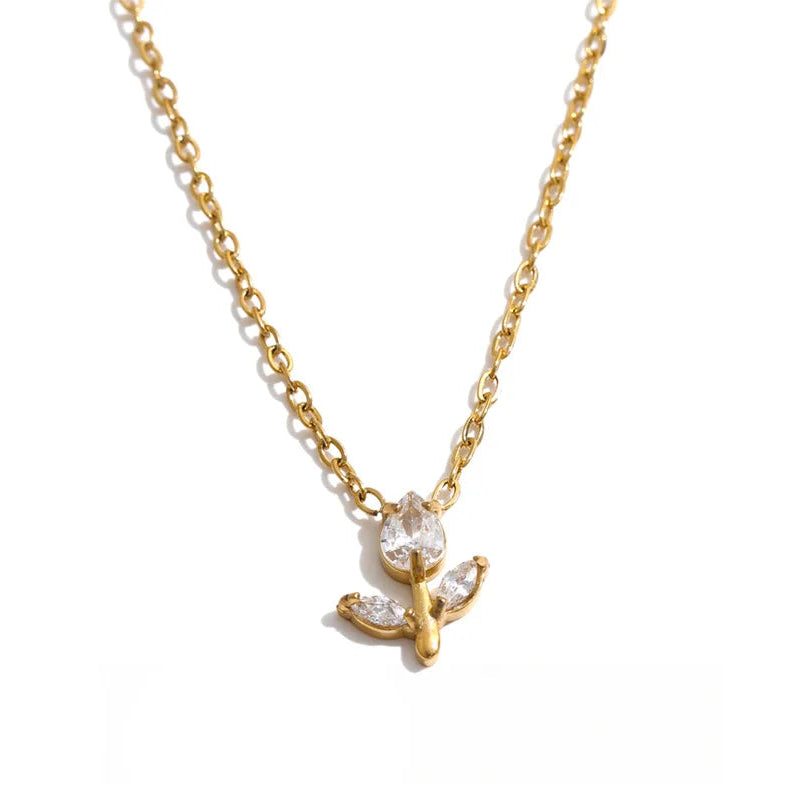 A delicate gold chain necklace featuring a small pendant with clear gemstones, displayed on a clean white background with a black script logo at the bottom.
