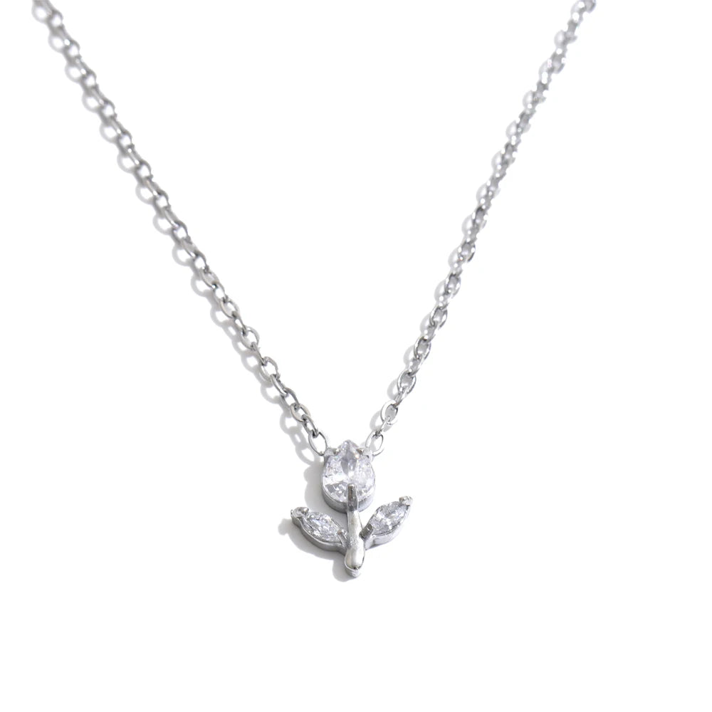 A delicate silver chain necklace featuring a small pendant with a clear faceted flower and two leaves, displayed against a solid white background.