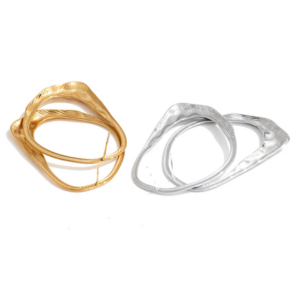Two textured abstract earringd one in polished gold and one in polished silver, displayed side-by-side on a clean white background.