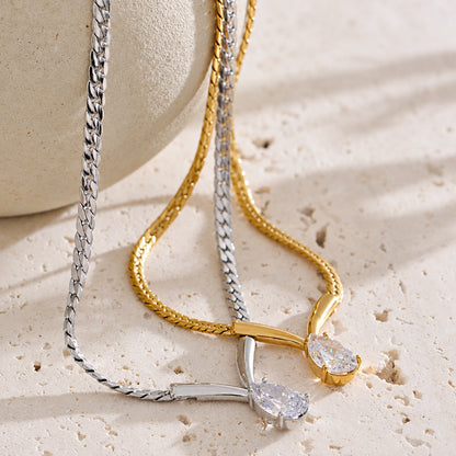 Two necklaces, one silver and one gold, on a textured surface with a blurred background.