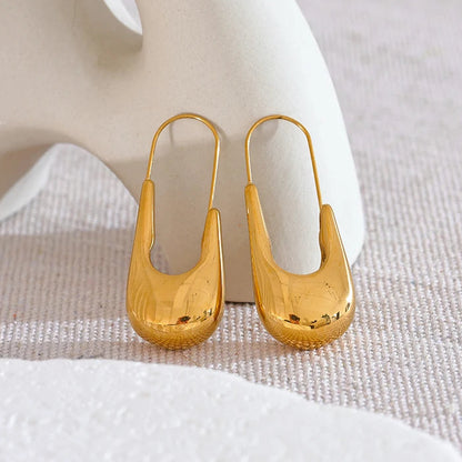 Gold earrings on a textured white surface