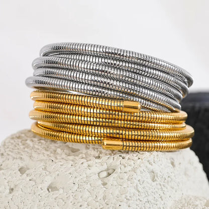 Stack of gold and silver bracelets on a textured surface
