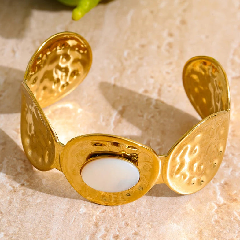 Gold bracelet with embossed designs on a textured surface