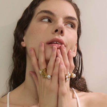 Woman wearing pearl rings with a neutral background
