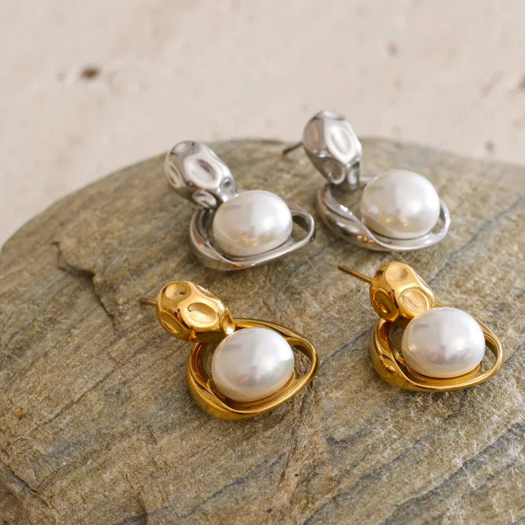 Pair of imitation pearl earrings on a stone surface