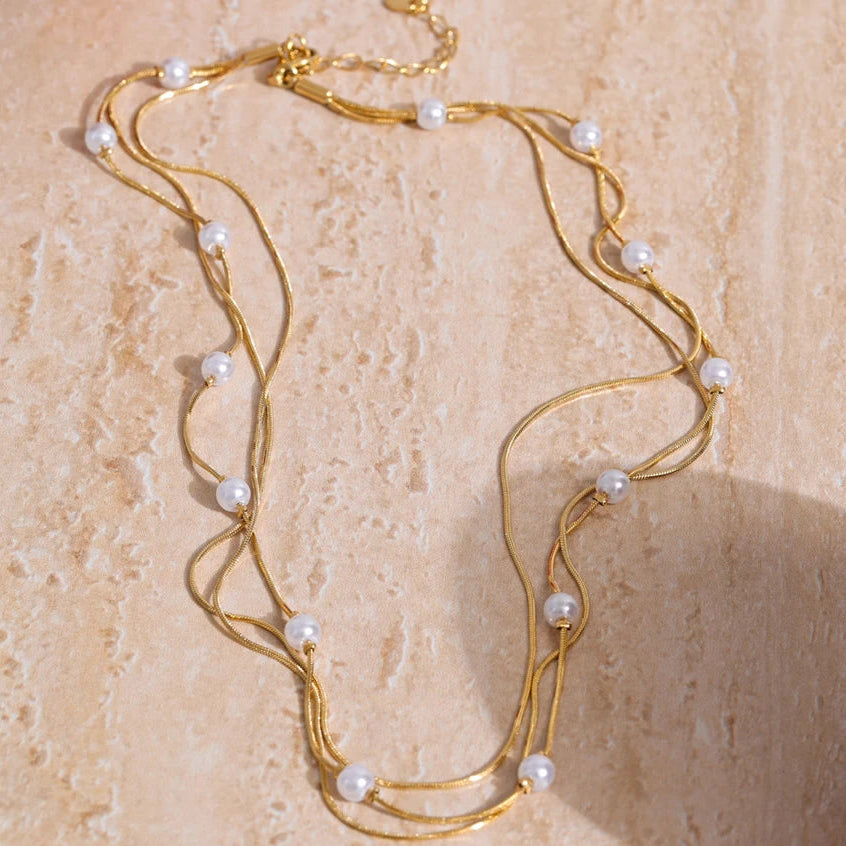Gold necklace with pearls on a beige surface