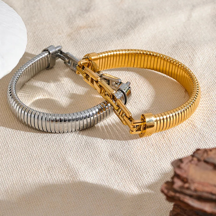 Gold and silver bracelets on a textured beige surface