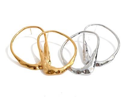 Three hammered hoop earrings in gold and silver finishes, arranged overlapping on a clean white background.