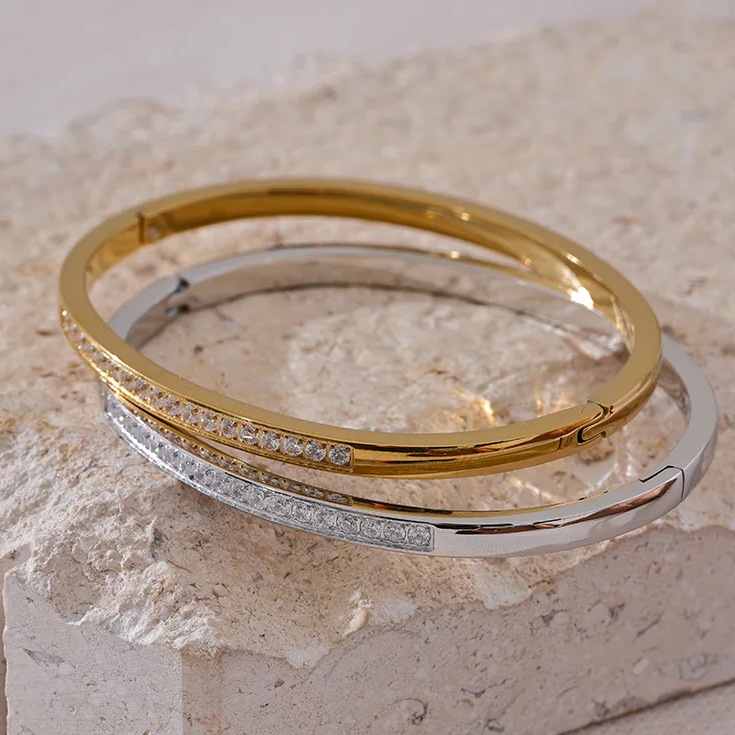 Gold and silver bangles on a textured stone surface