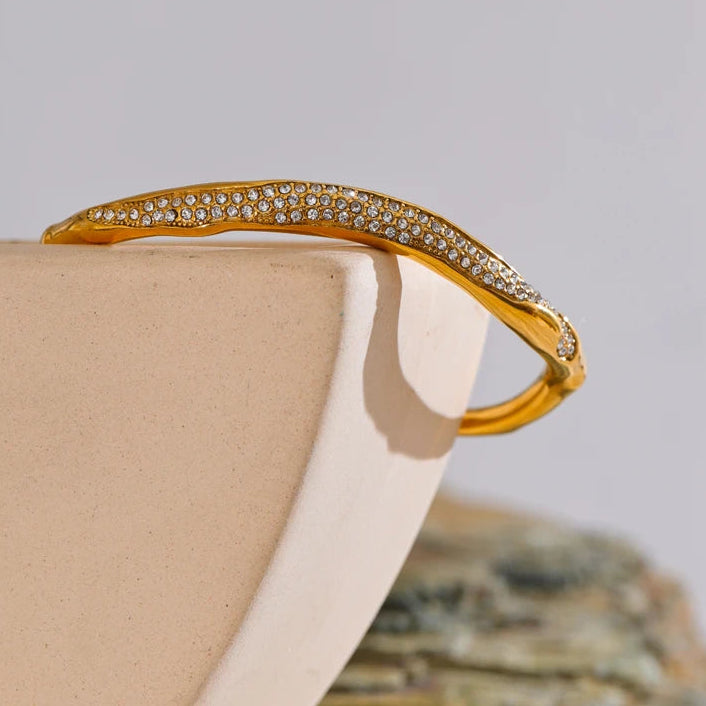 Gold bracelet with gemstones on a beige surface
