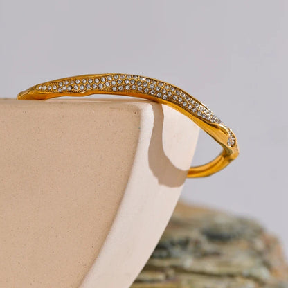 Gold bracelet with gemstones on a beige surface