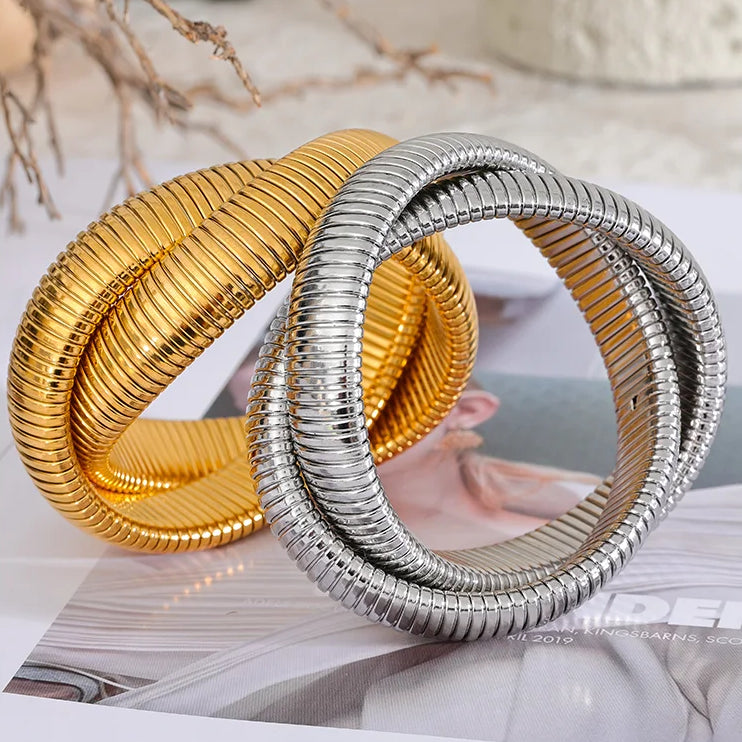 oan Bracelet — two intertwined snake chains twisted into a seamless infinity knot. Bold, sculptural styling with the flexible, second-skin feel of tubogas chain. Available in gold or silver — wear it as your only stack piece, it already does the work of two.