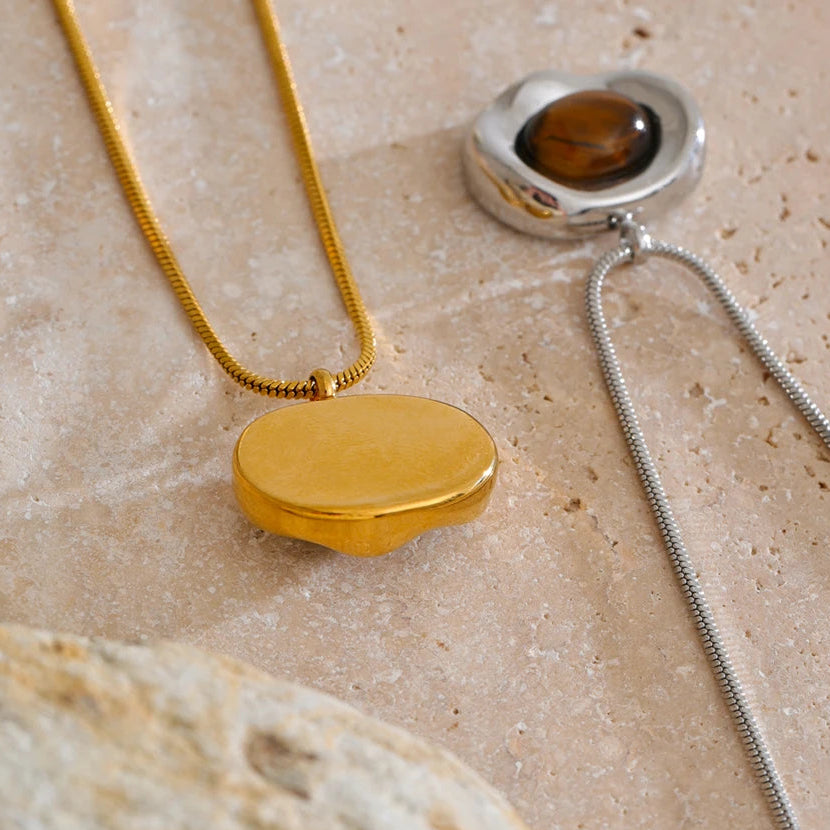 Gold and silver necklaces on a textured beige surface