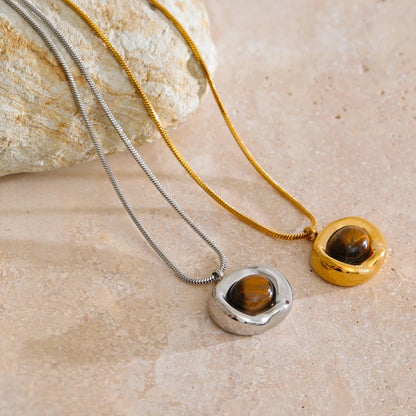 Two necklaces with tiger's eye pendants on a beige stone surface