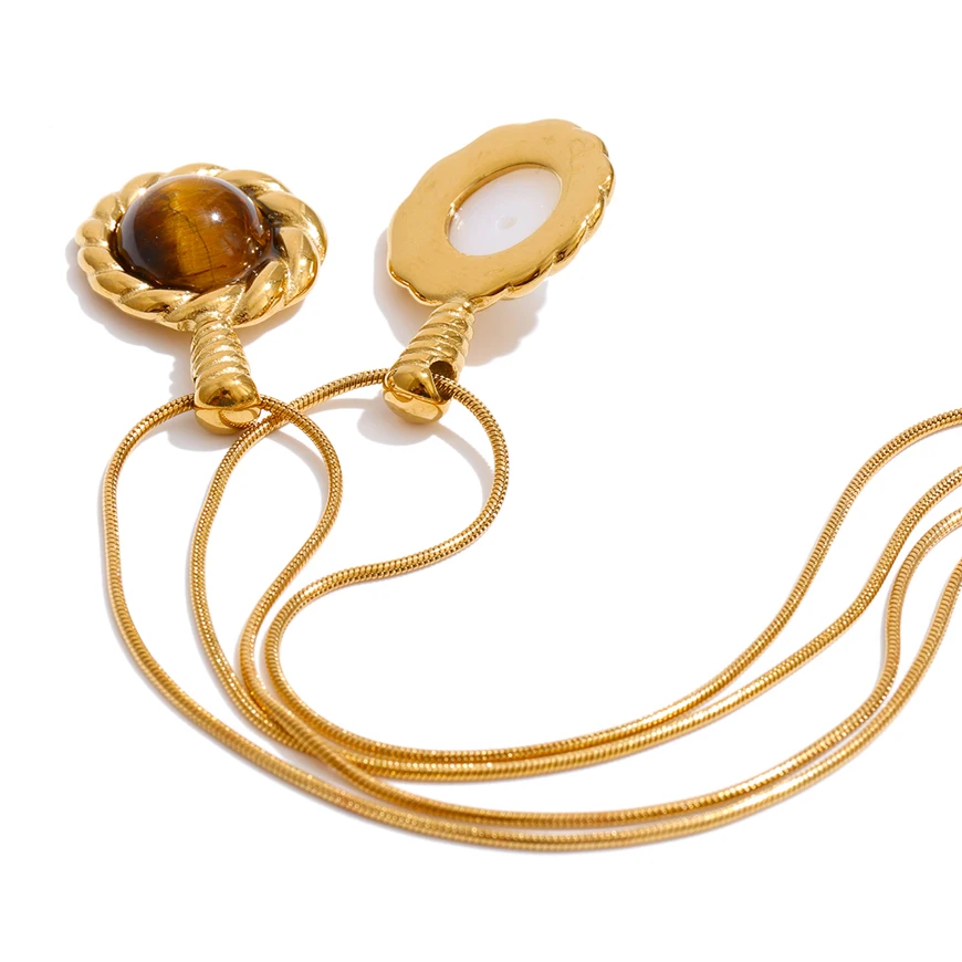 A gold-toned snake chain necklace with two oval pendant settings, one featuring a brown tiger's eye stone and the other with a white inlay