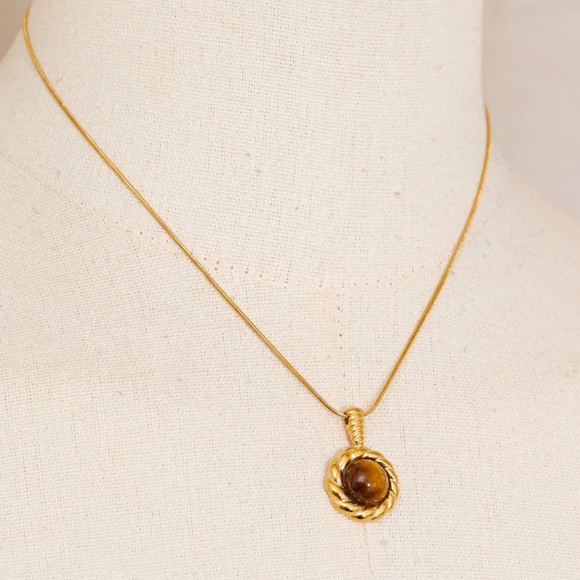 A gold chain necklace with a round textured gold pendant featuring a brown gemstone, stainless steel