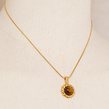 A gold chain necklace with a round textured gold pendant featuring a brown gemstone, stainless steel