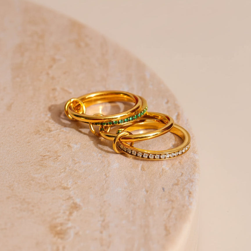 Gold rings with gemstones on a beige surface