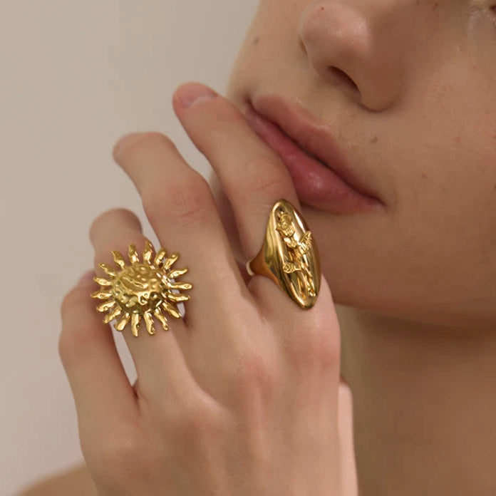Close-up of a person wearing gold rings on their fingers against a neutral background