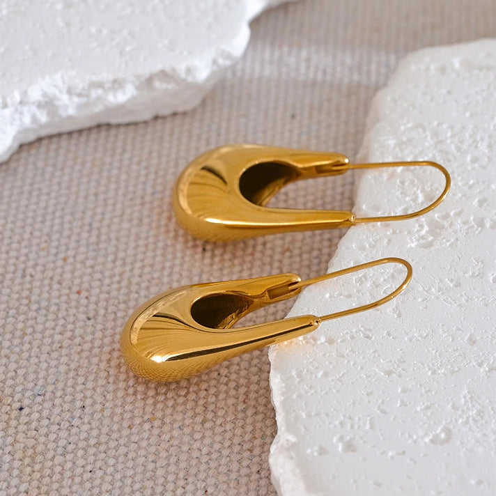 Gold earrings on a textured white surface